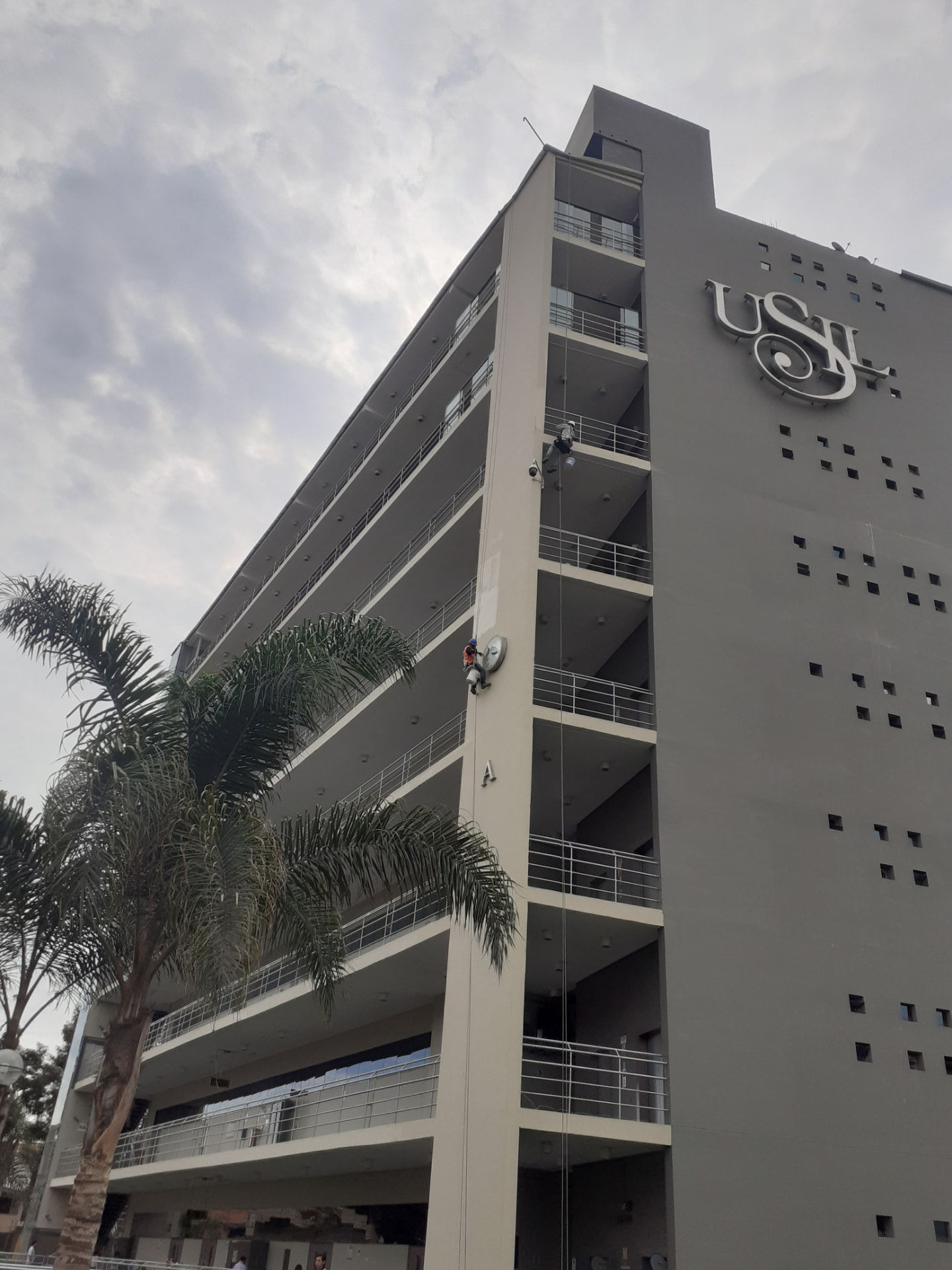 Técnicos en acceso por cuerdas pintando el pabellón A de la USIL