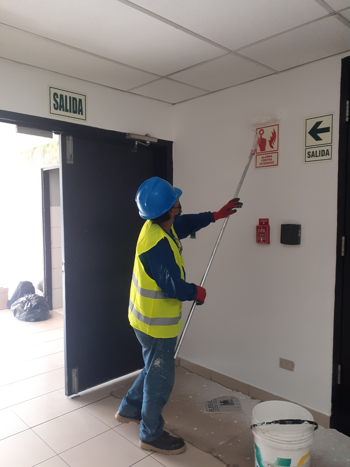 Operario pintando con rodillo el muro interior de un edificio