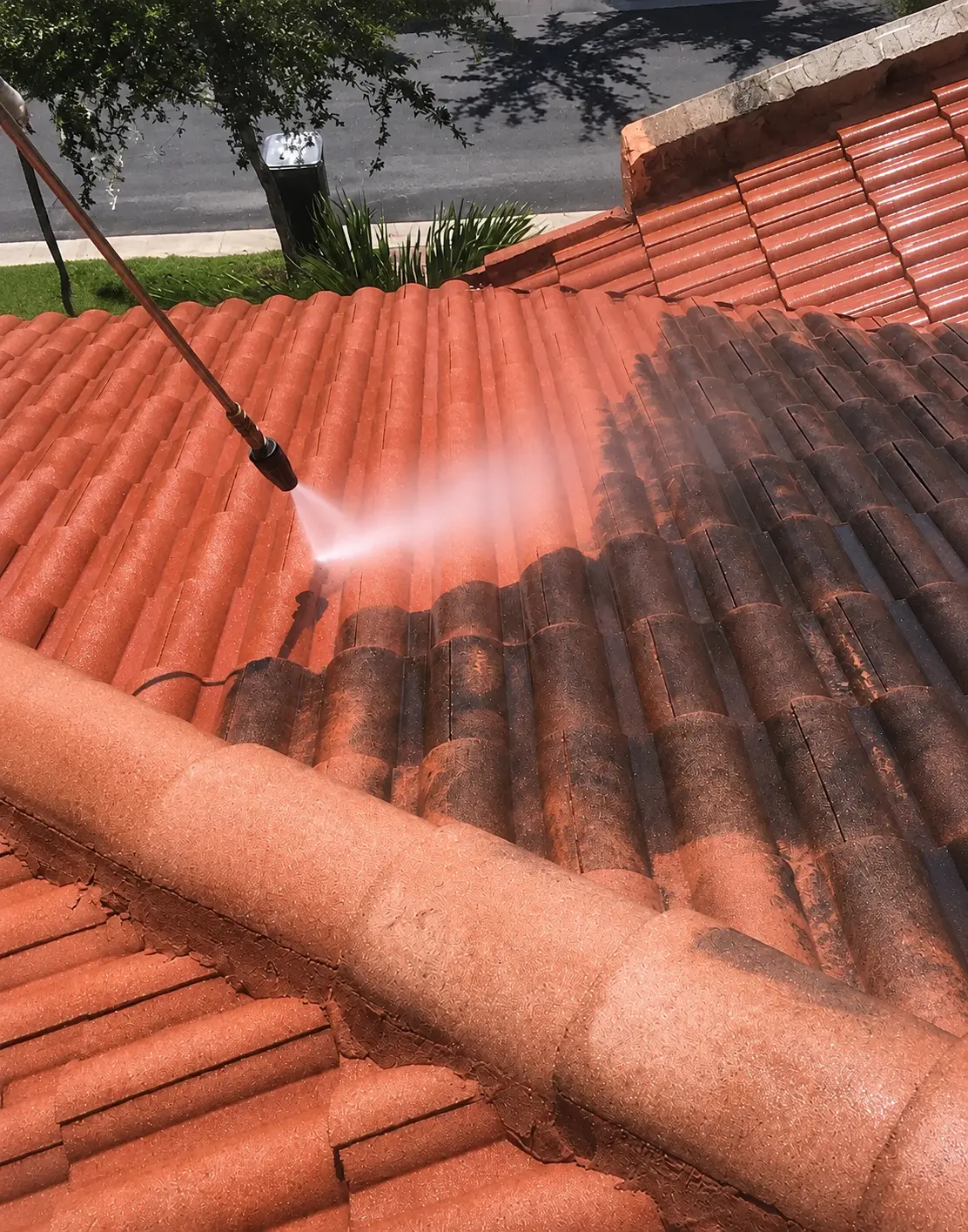 Trabajador hidrolavando tejas con musgo usando lanza de alta presión
