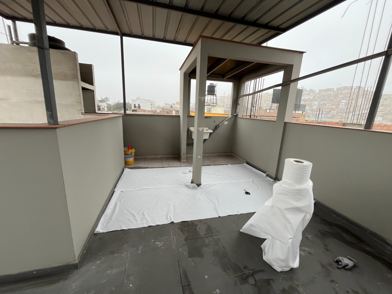 Operario aplicando membrana elastomérica en la azotea de un edificio